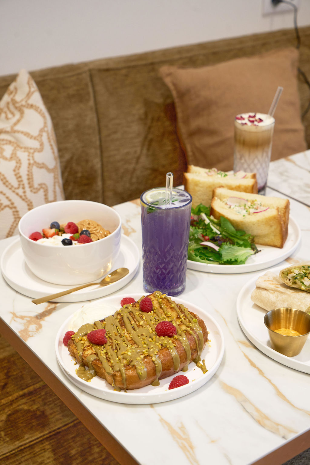 Table de brunch chez Cosy : bowl de granola, French toast pistache, sandwich et boissons